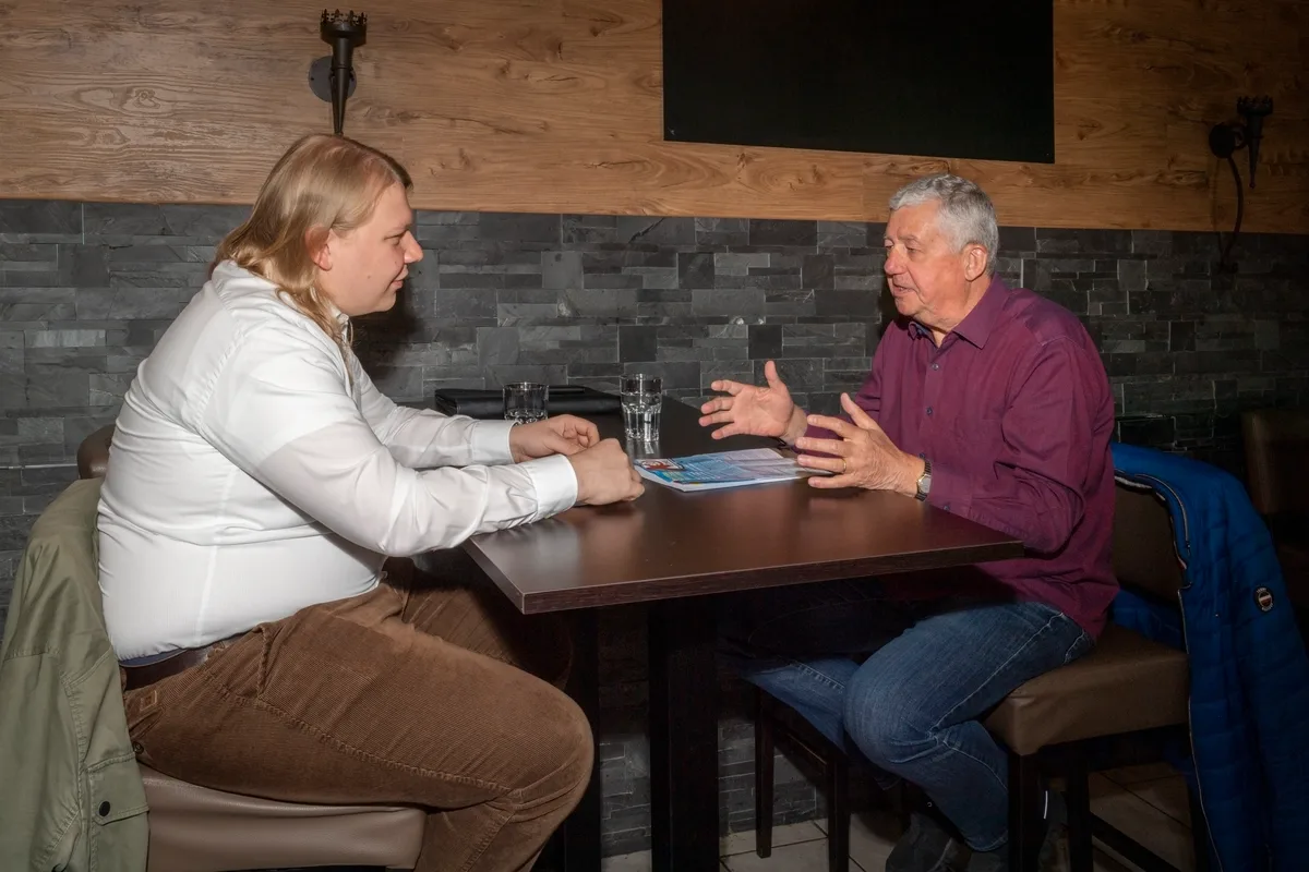 Zwei Männer sitzen an einem Tisch und diskutieren.